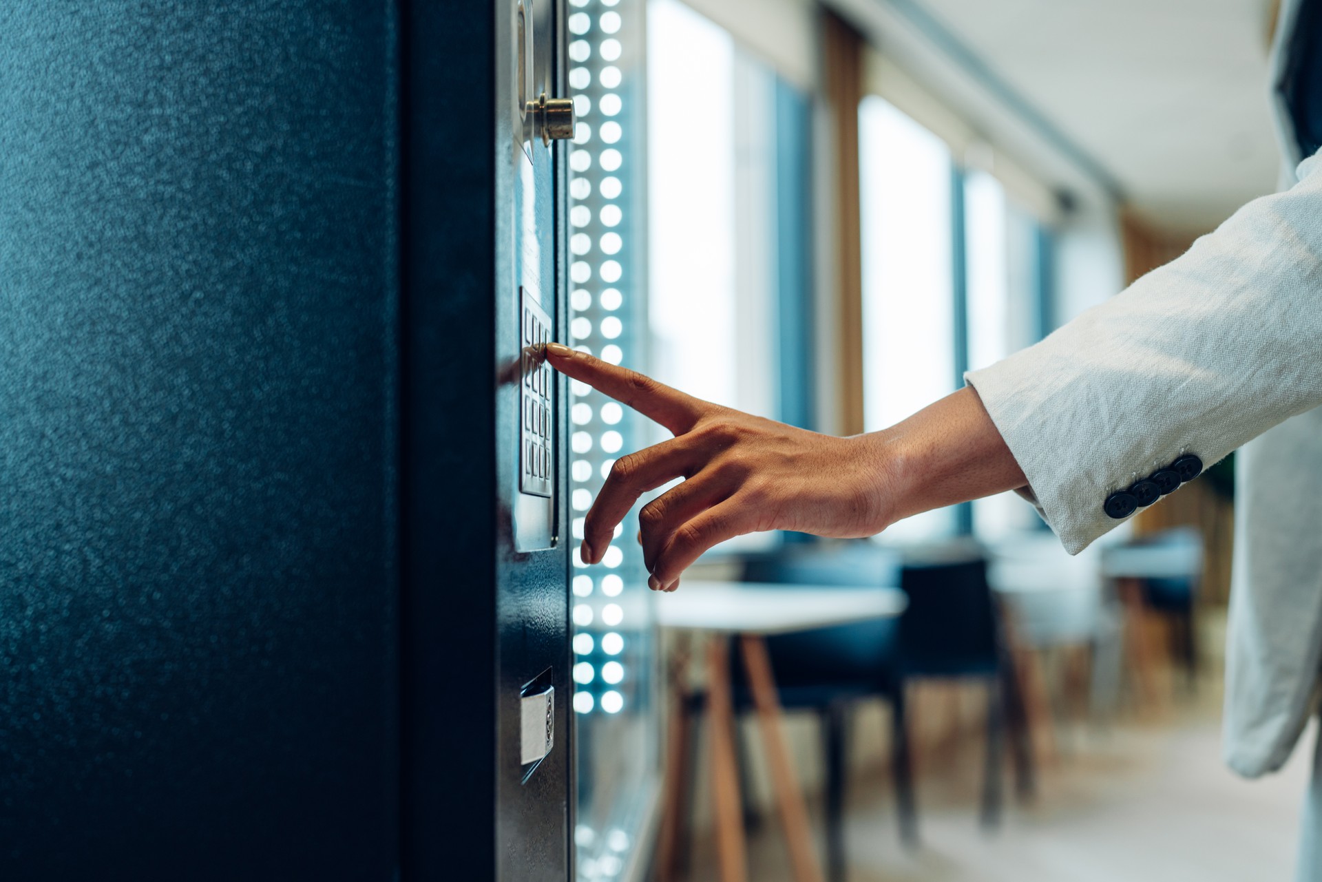 Close up view of woman's finger pushing number button on keyboard of snack vending machine. Self-used technology and consumption concept.